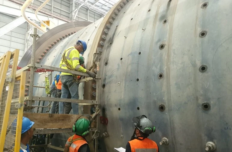 Technician on scaffolding tensioning bolts on a large mill shell